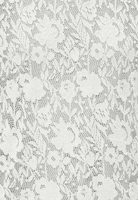 Biały koronkowy materiał z kwiatowymi wzorami o misternych detalach. Tekstura jest delikatna, o lekko przezroczystym wyglądzie.