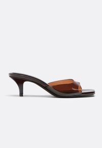Mule en cuir marron avec un petit talon kitten bas et une bride transparente marron sur le design à bout ouvert.