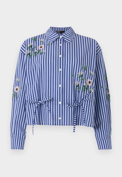 Chemise à rayures verticales bleu et blanc avec boutons et col, broderie florale sur les épaules et les manches, et détails noués à la taille.