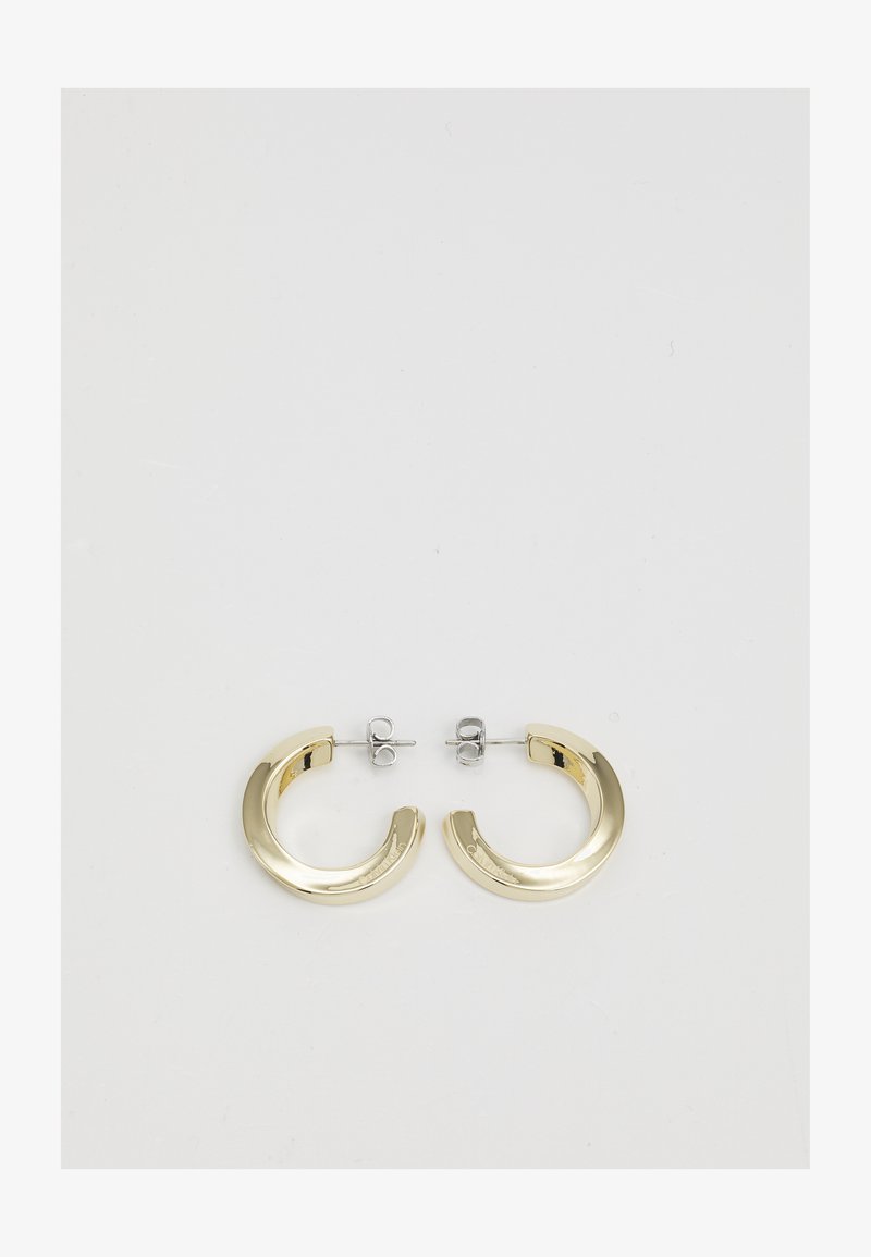 Złote metalowe kolczyki w kształcie kółek o gładkim, błyszczącym wykończeniu i częściowym okrągłym wzorze. Zamocowane na srebrnych zatyczkach i zapięciach.