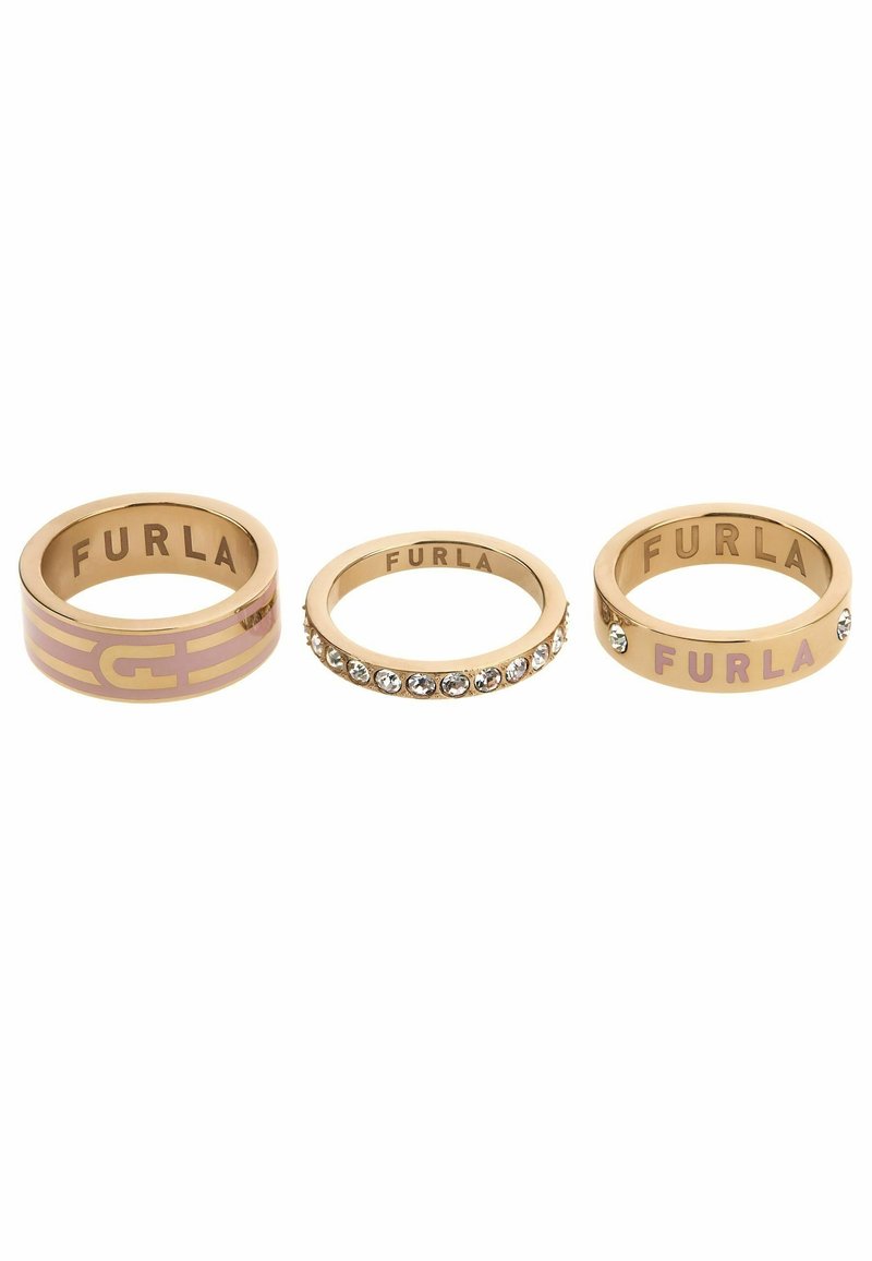 Trois bagues Furla dorées avec émail rose et ornements en cristal disposées en rangée sur fond blanc.