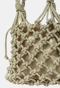 Borsa a rete metallica con perline e interno in raso; presenta un design annodato, una morbida drappeggiatura e una chiusura superiore arricciata.