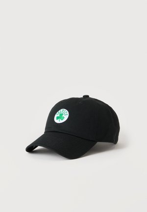 Casquette de baseball noire avec un trèfle vert et le mot "Celtics" brodé en vert sur un patch circulaire blanc à l'avant.