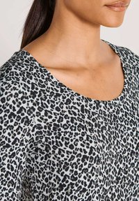 Schwarz-graues Leopardenmuster-Oberteil mit weitem Rundhalsausschnitt und weichem, strukturiertem Stoff, aus der Schulterperspektive gezeigt.