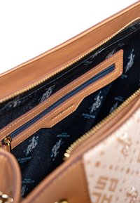 Tan läderväska med inredning i marinblått och flera zipfack. Designen inkluderar präglade logotyper och guld accenter.