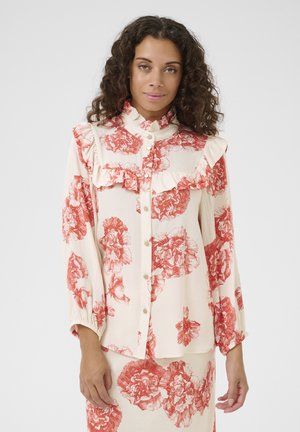 Bluse i floralmønster med en cremefarvet baggrund og røde blomstermotiver, flæsekrave, knappelukning foran og lange ærmer med elastiske manchetter.