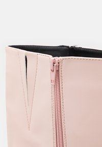 Rosa Kunstleder-Ankle-Boot mit seitlichem Reißverschluss, verfügt über ein elegantes Design und ein dezentes Ausschnittdetail am oberen Rand. Glatte Textur.