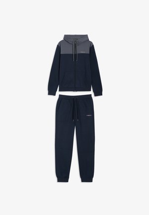 Sudadera con capucha azul marino con detalles grises y cremallera, combinada con pantalones deportivos a juego que tienen una cintura elástica y bolsillos laterales.