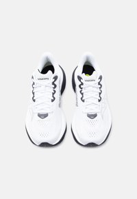 Ζευγάρι λευκά αθλητικά παπούτσια Saucony με μαύρες σόλες και λογότυπο, φωτογραφημένα από πάνω σε απλό φωτεινό φόντο.