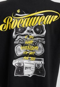 Černé tričko s grafickým designem boomboxu v stříbrné a žluté barvě, včetně nápisu "Rocawear" a fráze "Pokud to nechápete, není to pro vás."