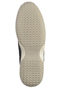 Basket noire avec une semelle en caoutchouc blanche. La semelle présente un motif en chevron avec de petites perforations et un logo en relief pour la respirabilité.