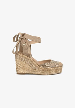 Sandalo con zeppa in espadrilles beige, con una tomaia in tessuto intrecciato, cinturino annodato, dettagli metallici applicati e suola in juta intrecciata.