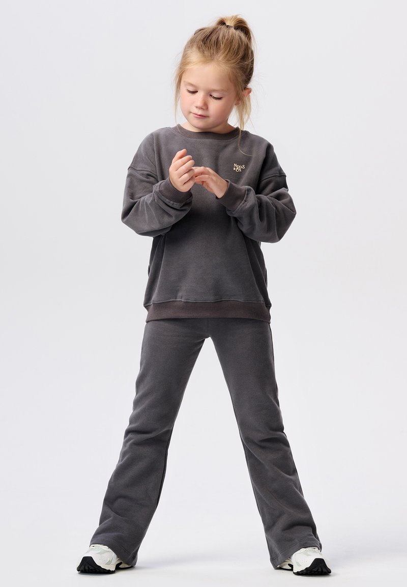 Szary zestaw składający się z bawełnianego swetra i spodni; sweter ma ściągacze przy rękawach oraz małe logo; spodnie są dzwony, mają gładką fakturę i luźny krój.