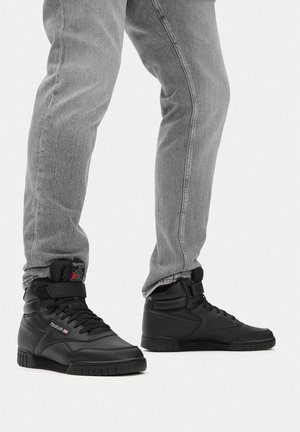 Czarne trampki za kostkę ze skóry gładkiej i teksturowanymi akcentami. Posiadają pasek, sznurowane zapięcie oraz teksturowaną gumową podeszwę.