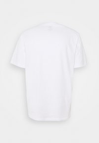 Bílá bavlněná trička s krátkými rukávy, kulatým výstřihem a rovým lemem. Na zadní straně nejsou viditelné vzory ani grafika.