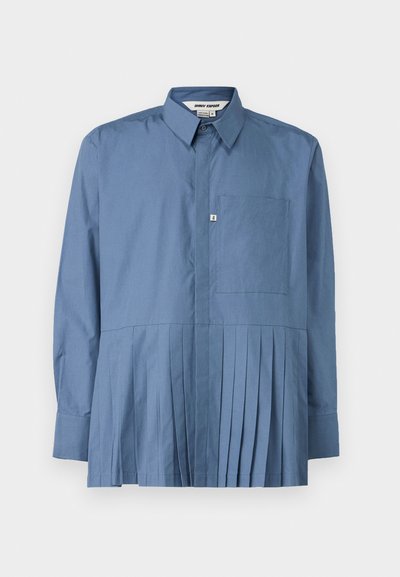 Chemise bleue à manches longues en coton, avec un devant à boutons, un col structuré, une poche unique sur la poitrine et une partie inférieure plissée.