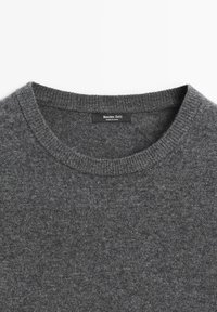 Grauer Pullover mit Rundhalsausschnitt aus weichem Strickstoff. Verfügt über einen gerippten Kragen und ein Markenetikett auf der Innenseite des Kragens.