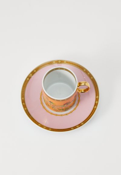 Κεραμική κούπα τσαγιού με πορτοκαλί λουλουδένιο σχέδιο, χρυσές λεπτομέρειες και χρυσή λαβή, συνοδευόμενη από ένα ροζ πιατάκι με χρυσό περίγραμμα.