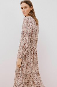 Langsleeve, vloeiende jurk met een bloemen-paisleypatroon in room, rood en blauw. Beschikt over een geraffineerde taille en een gelaagde onderzoom.