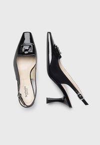 Scarpe slingback in vernice nera con punta affilata, tacco basso, dettagli in metallo argentato e rivestimento interno liscio.