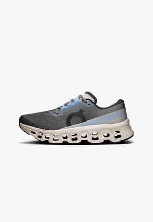 Chaussure de course grise et noire avec semelle beige présentant de grands trous de ventilation et le texte "ON RUNNING" sur le côté.