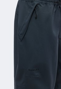 Κοντινή λήψη μαύρου παντελονιού Oakley με πλαϊνή τσέπη με φερμουάρ και ελαστική μέση.