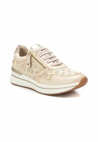 Zapatilla atlética beige con parte superior de piel perforada, acentos metálicos, media suela blanca y cordones con patrón. Cierre lateral para facilitar su uso.