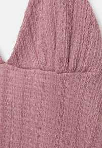 Texturovaná růžová látka s vrásčitým vzorem, s nařaseným designem na vrchu pro strukturovaný vzhled.
