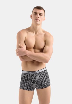 Boxer ajustados de patrón en blanco y negro con una cintura elástica que presenta el logo "Emporio Armani". El material parece suave y ceñido.