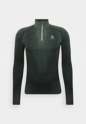 Maglia sportiva a maniche lunghe verde con colletto a metà zip, caratterizzata da un motivo testurizzato e una vestibilità aderente, realizzata in materiale elastico e traspirante.
