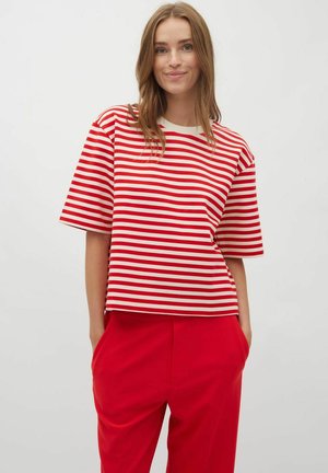 Red and white striped short-sleeve top with a round neckline, made of smooth fabric. Styled with loose-fit red trousers.