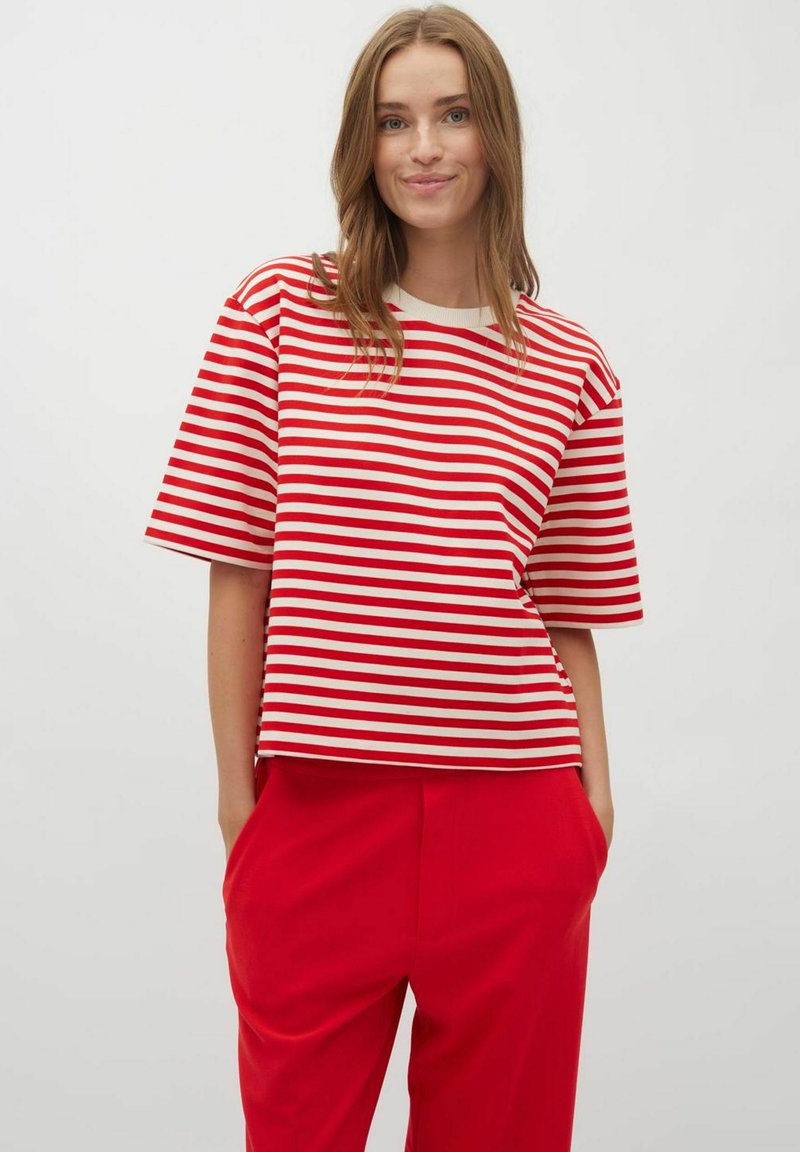Top de manga corta a rayas rojas y blancas con cuello redondo, hecho de una tela suave. Combinado con pantalones rojos de corte holgado.