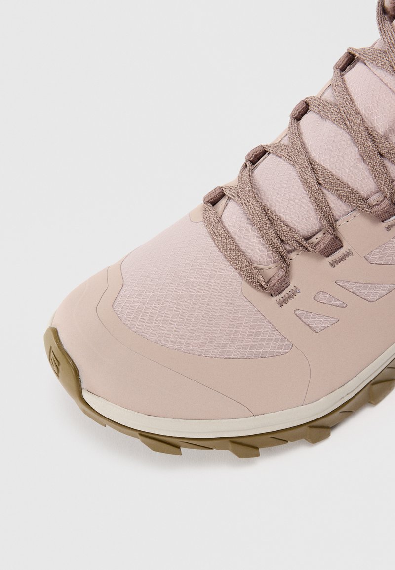 Chaussure de randonnée rose clair avec une tige en mesh, des lacets robustes, une semelle en caoutchouc et des accents à motifs pour une meilleure traction. Conçue pour une utilisation en extérieur.
