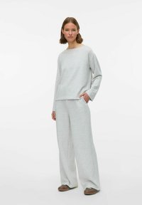 Gaišpelēka mājas apģērba komplekts, kas ietver garām piedurknēm t-kreklu ar plašu kakla izgriezumu un brīvi pieguļošas bikses ar sānu kabatām. Mīksta auduma tekstūra.