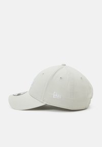 Boné de baseball cinza claro com aba curvada, apresentando logótipos bordados brancos na frente e lado, e uma superfície de tecido texturizada.