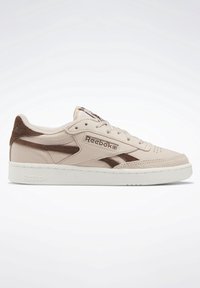Baskets Reebok basses beige et marron avec fermeture à lacets, logo sur le côté et sur la languette, et semelle en caoutchouc blanche sur fond blanc.