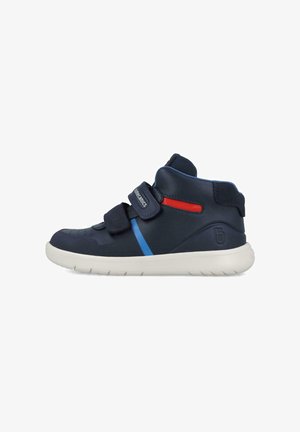 Zapatillas altas de marina con un acabado de cuero suave, que presentan acentos en azul y rojo, con dobles correas de velcro y una suela de goma blanca.