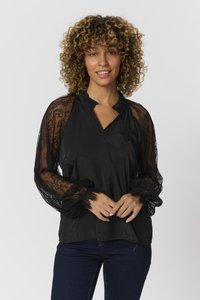 Juoda bluzonė su nėriniuotomis ilgomis rankovėmis ir voliotais apykaklėmis. Pasižymi laisvu įvoriu ir lengvu audiniu, suteikiančiu švelnų tekstūrą.