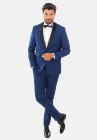 Tuxedo blu da uomo con rever in satin nero, abbinato a una camicia bianca e cravatta papillon nera. Scarpe in pelle verniciata nera completano il look.