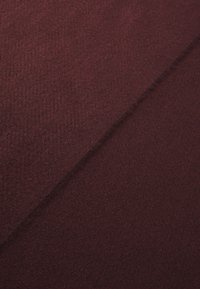 Burgundy textured fabric with a soft, fuzzy surface; features subtle patterns and a slightly diagonal fold, indicating the material's flexibility.
