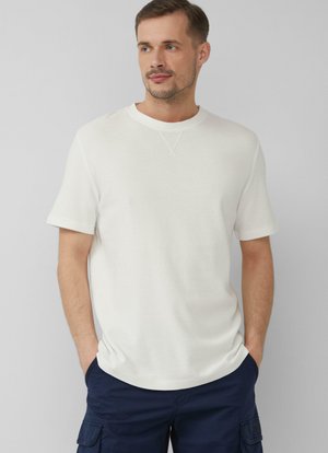 Witte T-shirt met korte mouwen en ronde hals, voorzien van een gestructureerde stof en subtiele stiksels op de schouders, gecombineerd met marineblauwe shorts.