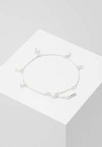 Silbernes Armband mit verschiedenen Anhängern, darunter Herzen und ein Anker, mit einem feinen Kettenmuster und einem Etikett, auf dem "PILGRIM" eingraviert ist.