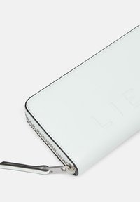 White leather wallet with embossed letters, black stitching, and a silver zipper. Includes a detachable keychain feature.