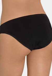 Svart bikini-bunn med en glatt, matte tekstur. Har en lavt skåret stil og enkle, rene linjer uten ekstra mønstre eller dekorasjoner.