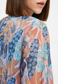 Blumenmuster-Stoff mit Blautönen, Lavendel und Pfirsich sowie grünen Akzenten; leicht, strukturiert und fließendes Design.