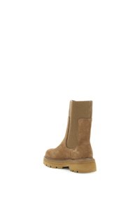 Bottine en suede marron avec des panneaux latéraux élastiques nervurés et une semelle en caoutchouc épaisse. Détails de couture le long de la semelle et texture lisse.