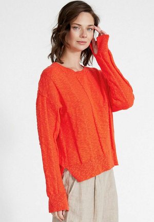 Maglione lavorato a maglia arancione brillante con una finitura testurizzata, scollo tondo e maniche lunghe leggermente sovradimensionate. Presenta un orlo corto.