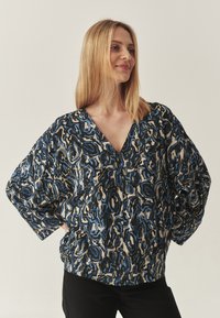 V-Ausschnitt-Bluse mit einem blau-schwarzen abstrakten Muster, lockeren Ärmeln und einem entspannten Schnitt, aus leichtem Stoff gefertigt.