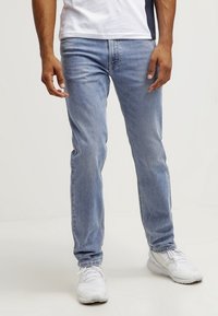 Vaqueros de mezclilla azul claro con un corte slim, diseño de pierna recta, sutil desgaste y estilo clásico de cinco bolsillos.