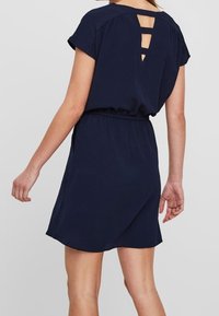 Námořnická modrá krátká šaty s krátkými rukávy, elastickým pasem a výstřihem na zádech. Hladká tkanina se splývavým siluetem.